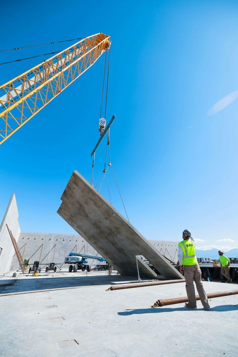 Construction worker guiding a crane lifting a concrete wall panel